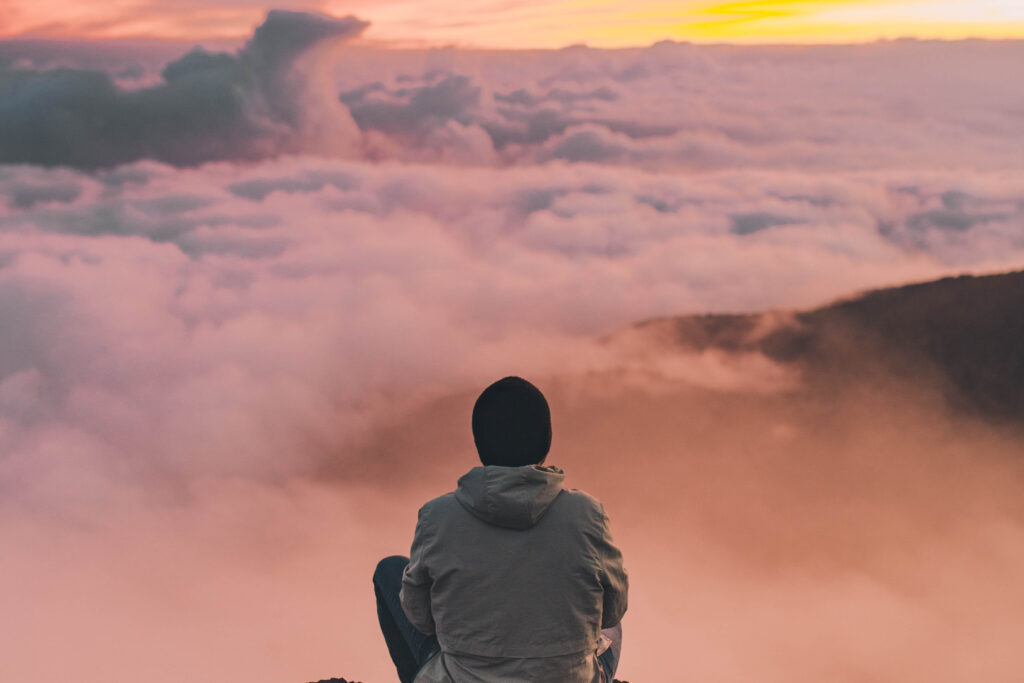 Homme contemplant les nuages depuis le sommet d'une montagne